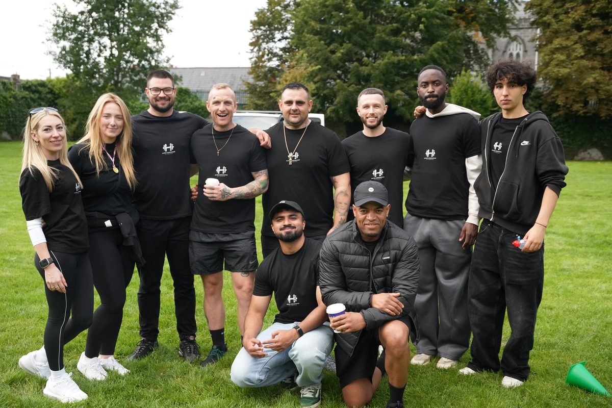 Ten Community Day volunteers in Hyper Endurance Fitness t shirts posing together on the grass at People's Park