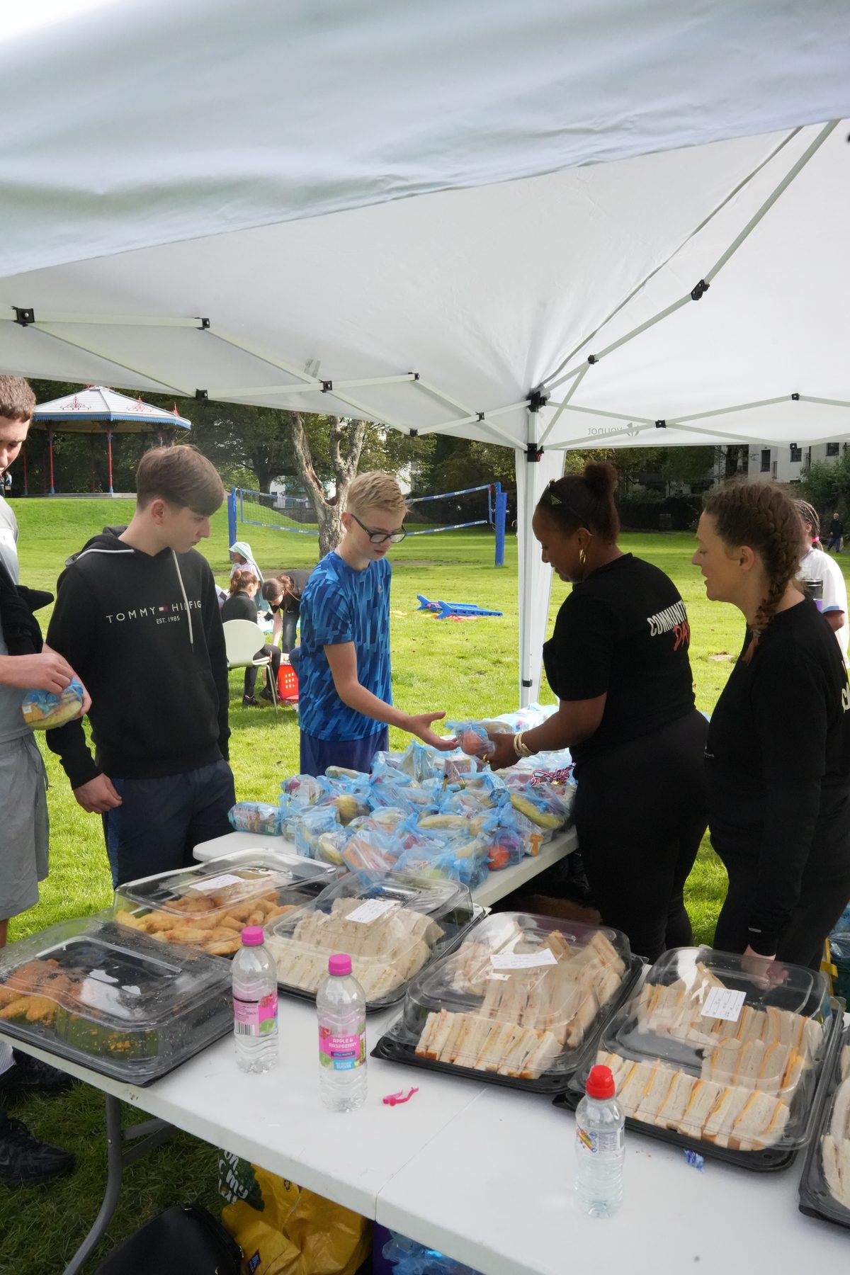 Volunteers handing out bags of healthy snacks to young people at the food table